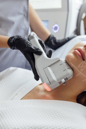 Portrait of relaxed young female client getting SMAS ultrasound face lifting massage